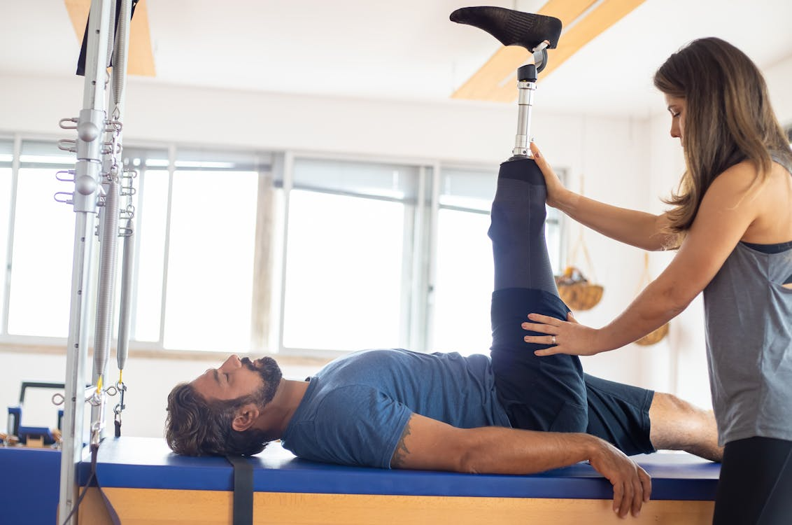 Personal trainer assists an amputee with physiotherapy