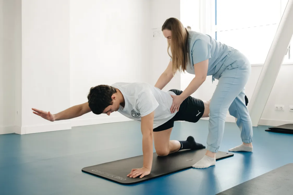 A physiotherapist guides movement on a mat